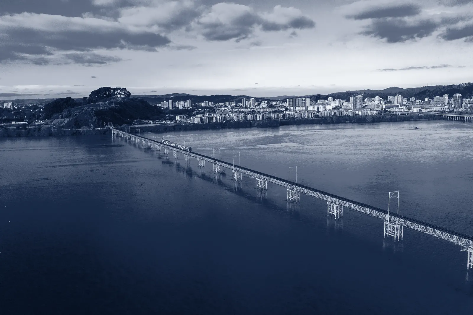 El puente ferroviario sobre el río Biobío, con Concepción al fondo, virado a azul